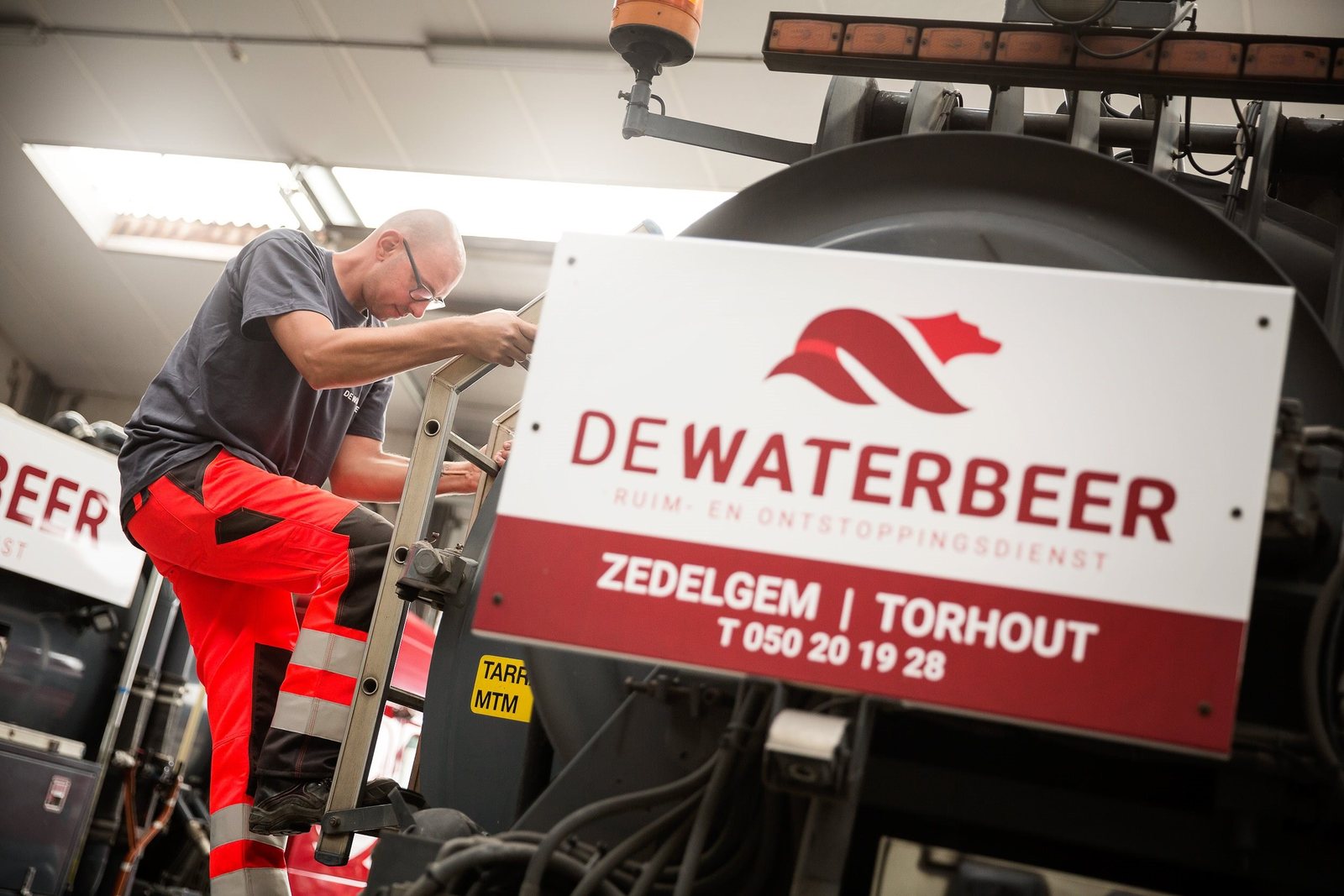 Vakman bij een bord van De Waterbeer op de wagen
