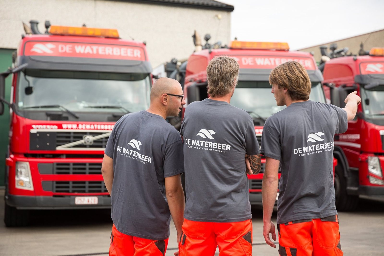 Drie vakmannen voor de rode ruimwagens